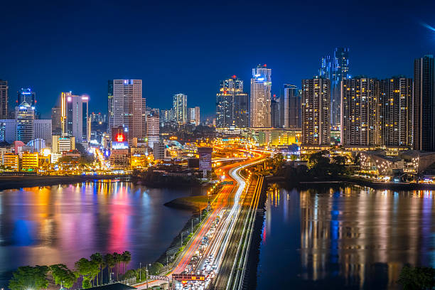 Night skyline of Johor Bahru with illuminated skyscrapers, highway light trails, and waterfront reflections, Johor, Malaysia